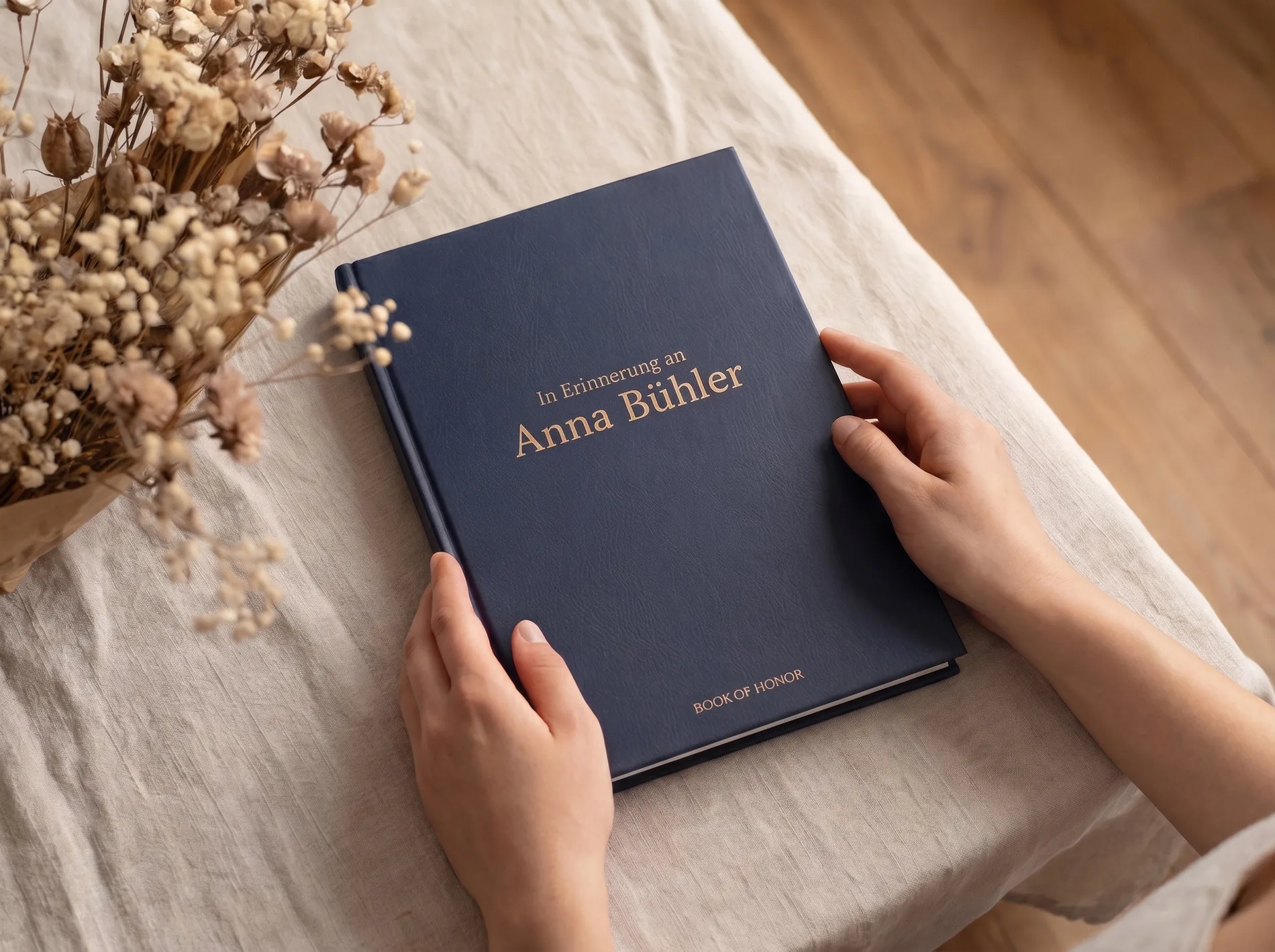 Hände halten das Book of Honor Gedenkbuch mit goldenem Namensdruck